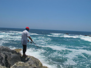 Pesca in Oman Sud dalla costa, foto di uno spot sulle coste nel Dhofar, intorno a Salalah nel Mar Arabico, parte dell' Oceano Indiano. Il pescatore sta effettuando la pesca a spinning.